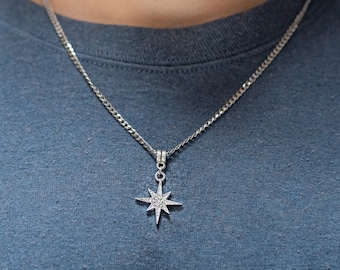 May include: A silver chain necklace with a star-shaped pendant. The pendant has small, clear stones set into it.