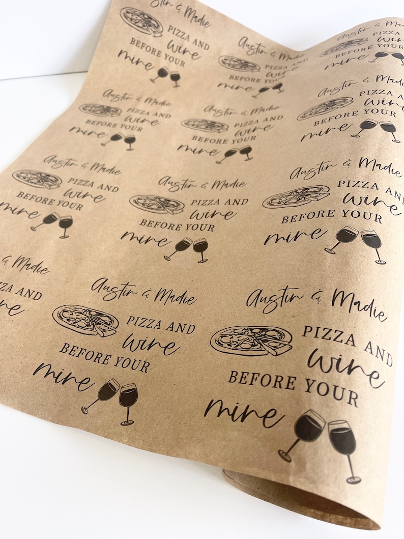 May include: Brown paper wrapping paper with a repeating pattern of a pizza slice and wine glasses with the text "Austin & Madie Pizza and Wine Before Your Mine" printed on it.