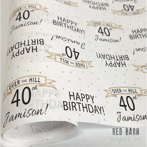 May include: White wrapping paper with a repeating pattern of gold polka dots and the text "Over the Hill 40th Jamison! Happy Birthday!" in black. The text is repeated in different orientations throughout the paper.