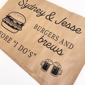 May include: Brown paper bags with black text and illustrations. The text reads "Sydney & Jesse Burgers and Brews Before "I Do's"". The illustration is of a hamburger and two beer mugs.