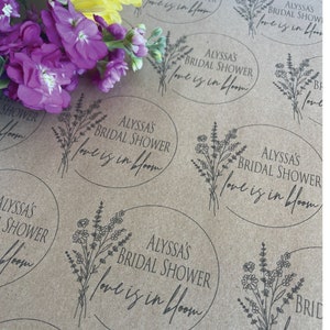May include: Brown paper gift wrap with a repeating pattern of floral designs and the text "Alyssa's Bridal Shower Love is in Bloom".