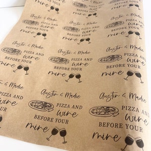 May include: Brown paper gift wrap with a repeating pattern of pizza slices and wine glasses. The text "Austin & Madie Pizza and Wine Before Your Mine" is printed on the paper.