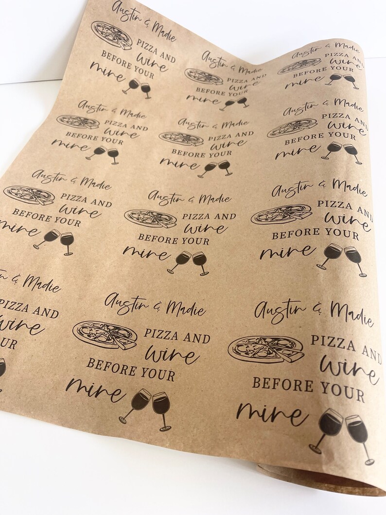 May include: Brown paper gift wrap with a repeating pattern of pizza slices and wine glasses. The text "Austin & Madie Pizza and Wine Before Your Mine" is printed on the paper.
