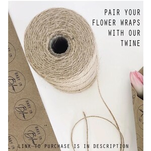May include: A roll of natural twine with a brown and beige color gradient. The twine is on a white surface with brown paper wrapping with the text "BABY IN BLOOM" printed on it. The text "PAIR YOUR FLOWER WRAPS WITH OUR TWINE" is printed in black on a white background. The text "LINK TO PURCHASE IS IN DESCRIPTION" is printed in black on a white background.