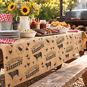 May include: A tan paper table runner featuring a repeating black print of the text Mitchell & Son's Barbecue, silhouettes of cows and chickens, and circular stamps. The runner is draped over a wooden table set for an outdoor meal.