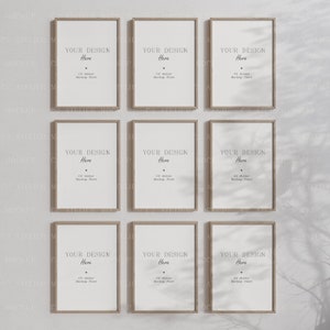 Puede incluir: Nueve carteles enmarcados en madera con montajes blancos y un marco de madera marrón claro. Los carteles tienen el texto "YOUR DESIGN Here" con el texto "C2 Atelier Mockup Store" debajo. Los carteles están colgados en una pared blanca con sombras de una ventana.