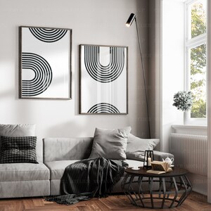 May include: A living room interior with a gray couch, a black and white geometric print on the wall, a black floor lamp, a black coffee table, and a potted plant.