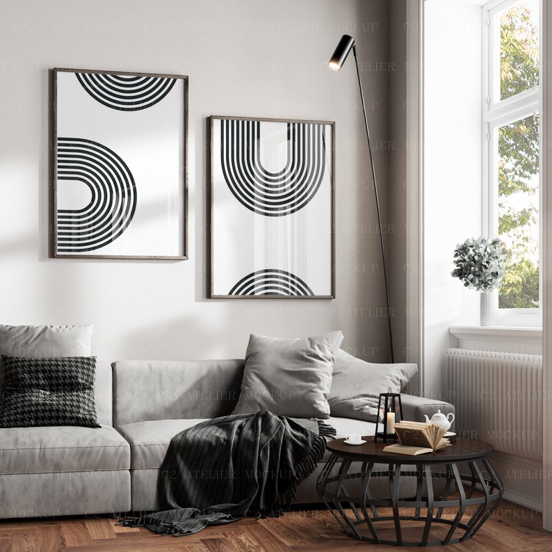 May include: A living room interior with a gray couch, a black and white geometric print on the wall, a black floor lamp, a black coffee table, and a potted plant.