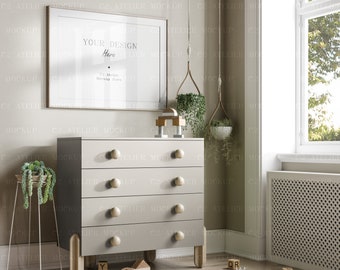May include: A white dresser with four drawers and wooden legs. The dresser is in a room with a window, a framed picture, and a hanging plant. The picture frame has a white mat and a light wood frame. The picture frame has the text "Your Design Here" and "C2 Atelier Mockup Store". There are wooden toy blocks and a toy train on the floor in front of the dresser.