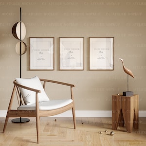 Puede incluir: Tres marcos de fotos de madera con un acabado marrón claro, colgados en una pared beige. Los marcos están vacíos y tienen el texto "Your Design Here" impreso en el interior. Los marcos están colgados sobre una silla de madera con un cojín blanco, una mesa auxiliar de madera y una escultura de pájaro de madera.