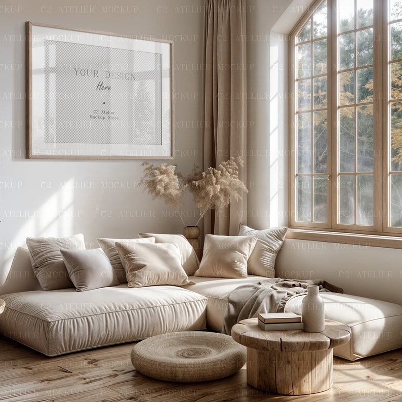 Peut inclure: Un canap&eacute; d'angle beige avec plusieurs coussins est plac&eacute; dans un salon avec une grande fen&ecirc;tre. Le canap&eacute; est devant un mur blanc avec un tableau encadr&eacute; au-dessus. Le tableau a un fond transparent et le texte "Your Design Here" et "C2 Atelier Mockup Store". Le sol est en planches de bois.