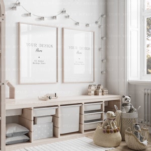 May include: Two white picture frames with the text "YOUR DESIGN Here" and "C2 Atelier Mockup Store" hanging on a white wall above a wooden shelf with storage bins, toys, and a basket of stuffed animals.
