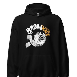 Peut inclure: Sweat-shirt à capuche noir avec un motif blanc en spirale et le texte "BROADCAST" en orange avec les mots "MAMA SOUND" en blanc plus petit.