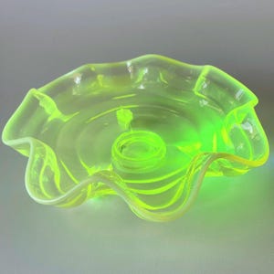 Puede incluir: Un cuenco de cristal amarillo neón translúcido con un borde ondulado y rizado y una base circular. El cuenco tiene un acabado liso y brillante con un tono verde lima vibrante y distintivo que capta la luz de forma luminosa.