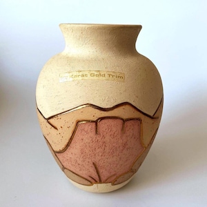 Peut inclure: Un vase en céramique beige avec une surface texturée et un corps arrondi. Le vase présente un motif avec des nuances de marron et de rose, rehaussé d'une bordure dorée. Le texte "Karät Gold Trim" est visible à l'avant.
