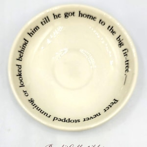 Puede incluir: Un platillo de cerámica blanco con texto negro que dice "Peter nunca dejó de correr o mirar hacia atrás hasta que llegó a casa al gran abeto."