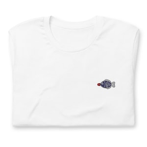 May include: White t-shirt with a small embroidered blue fish with a red mouth.