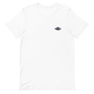 May include: White t-shirt with a small embroidered blue fish with a red fin.