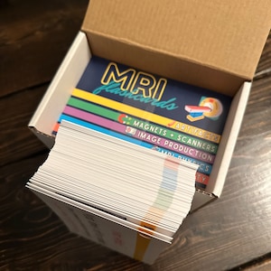May include: A box of MRI flashcards with a colourful design. The box is open and the flashcards are stacked inside. The flashcards have different coloured borders and the text "MRI flashcards" is printed on the top card.