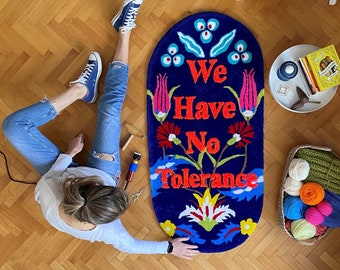 May include: A blue oval rug with a floral design and the text "We Have No Tolerance" in red letters.