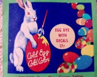 Könnte beinhalten: Vintage Ostereierfarben-Box mit einem weißen Hasen, der ein rotes Ei bemalt. Der Text lautet "Cold Egg Cold Color" und "Egg Dye with Decals". Die Farben sind Rose, Blau, Grün und Gelb, ideal zum Färben von Ostereiern.
