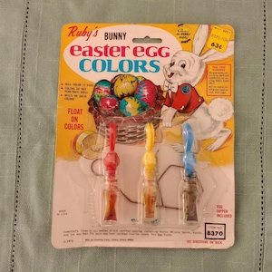 May include: Vintage Ruby's Bunny Easter Egg Colors kit. The packaging features a cartoon bunny and basket of colorful eggs. Includes three bottles of dye in red, yellow, and blue with egg dippers. Made in the USA.
