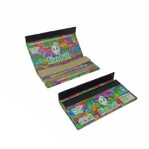 May include: A colorful, psychedelic rolling paper pack with a green alien logo and the text "Alien Puff" on the front. The pack is a magnet pack and has a black flap.