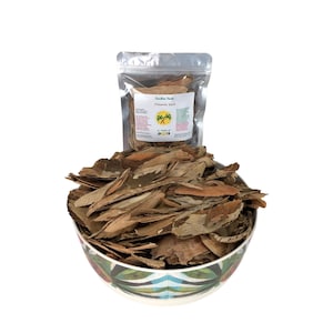 May include: A ceramic bowl filled with dried pimento bark, with a clear bag of pimento bark in the background. The bag has a label that reads "Sunshine Herbs Pimento Bark A Taste of Jamaica". The bowl has a colorful floral design.