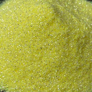 May include: Close-up of a pile of fine, yellow glitter with a sparkling, iridescent sheen. The glitter particles are small and densely packed, creating a textured surface. The glitter reflects light, creating a shimmering effect. Ideal for crafts and decorations.