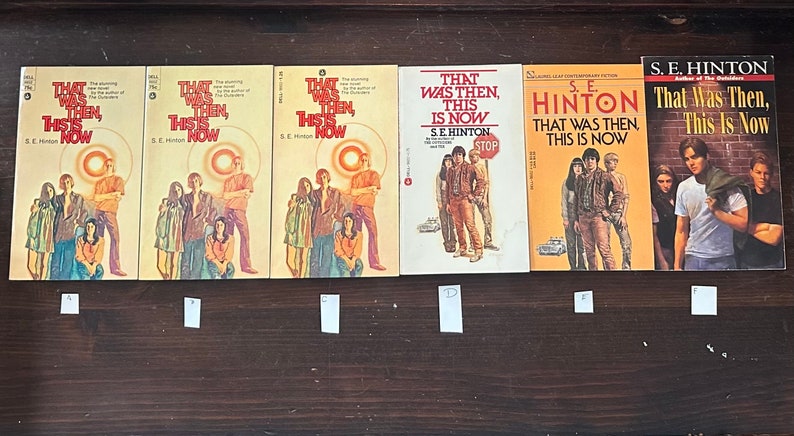 May include: Five paperback copies of the book "That Was Then, This Is Now" by S.E. Hinton. The covers feature different illustrations of the characters from the book.
