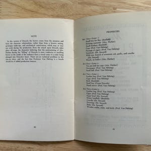 Może przedstawiać: Otwarta książka pokazująca strony 40 i 41. Lewa strona zawiera notatkę na temat produkcji Drakuli. Prawa strona wymienia rekwizyty do aktu pierwszego i drugiego, w tym przedmioty takie jak małe pudełko na muchy, przybory do rob&oacute;tek ręcznych i drewniany młotek.
