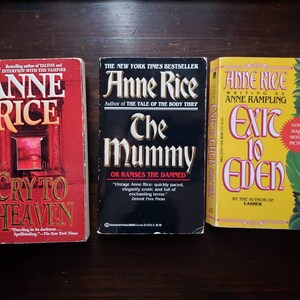 May include: Three paperback books by Anne Rice, with titles "Cry to Heaven", "The Mummy", and "Exit to Eden". The books are all in different colors, with the first book being red, the second black, and the third yellow.