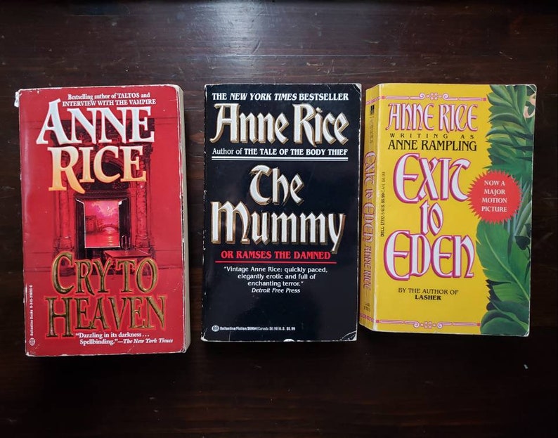 May include: Three paperback books by Anne Rice, with titles "Cry to Heaven", "The Mummy", and "Exit to Eden". The books are all in different colors, with the first book being red, the second black, and the third yellow.