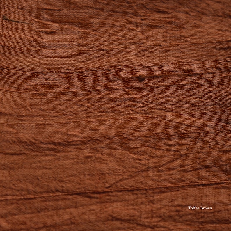 May include: Close-up of a textured fabric in a warm toffee brown color. The fabric has horizontal lines and a slightly uneven surface, with the words "Toffee Brown" in the bottom right corner.