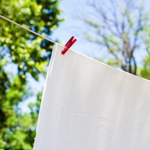 May include: A white sheet hanging on a clothesline with a red clothespin.
