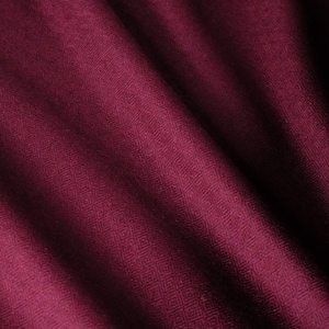 Puede incluir: Una tela de color burdeos intenso que presenta un sutil patrón geométrico de diamantes repetitivos tejido en el material. El tejido muestra pliegues y sombras suaves, resaltando la textura intrincada y el color rojo oscuro constante en toda la superficie.