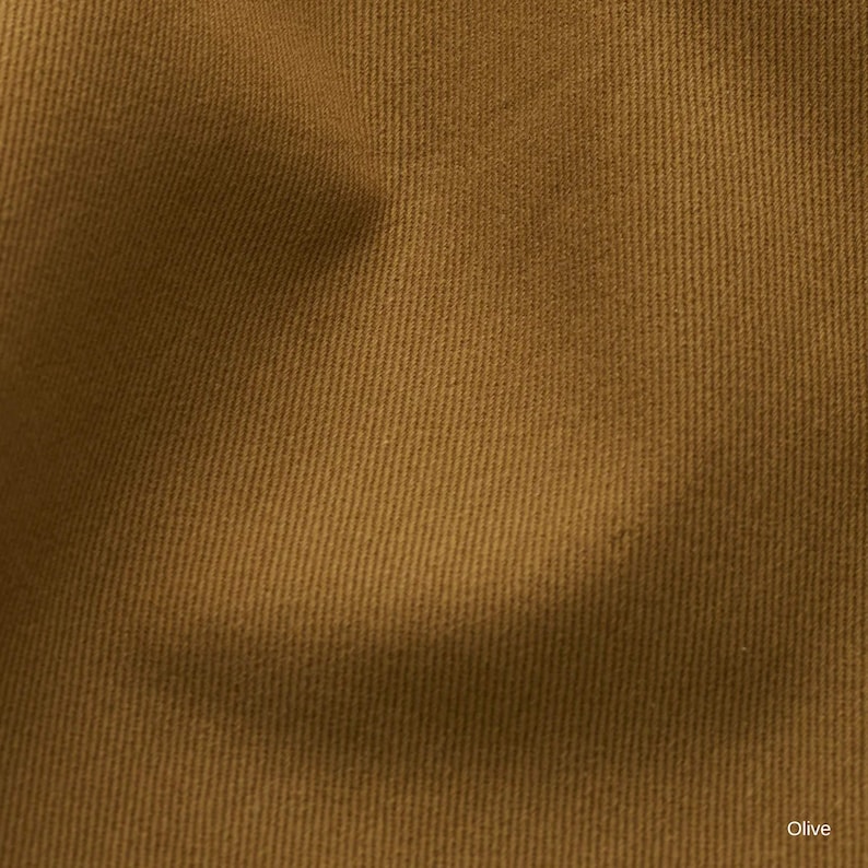 K&ouml;nnte beinhalten: Eine Nahaufnahme eines Stoffes mit einem ausgepr&auml;gten diagonalen K&ouml;perbindungsmuster in einer einfarbigen olivbraunen Farbe. Das Material weist eine gleichm&auml;&szlig;ige Textur mit sichtbaren parallelen Rippen auf der Textiloberfl&auml;che auf.