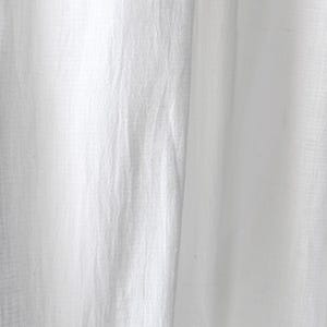 May include: Close-up of white fabric with a textured appearance. The fabric has a slightly wrinkled look, with vertical folds and subtle variations in light and shadow. The material appears to be lightweight and possibly linen or cotton.