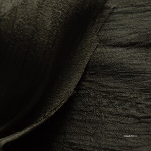 May include: Close-up of a textured fabric in a dark olive green color. The fabric has a subtle sheen and a slightly rough texture, with visible horizontal lines. The words "Black Olive" are in the bottom right corner.