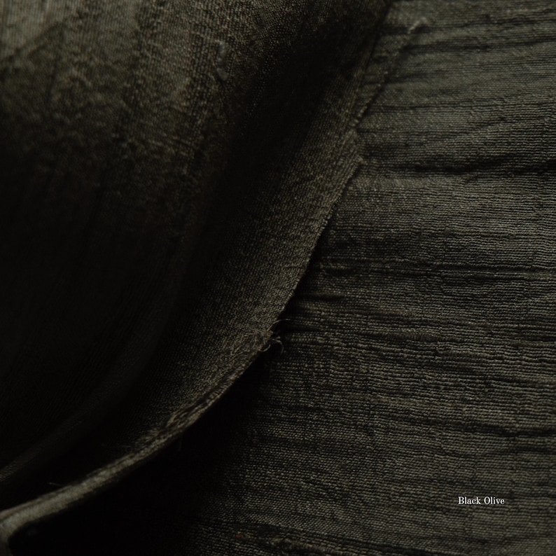 May include: Close-up of a textured fabric in a dark olive green color. The fabric has a subtle sheen and a slightly rough texture, with visible horizontal lines. The words "Black Olive" are in the bottom right corner.