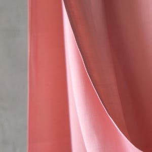 Puede incluir: Primer plano de tela fluida y en capas en tonos rosa y coral. La tela parece suave y transl&uacute;cida, con sutiles variaciones de color y textura. Los pliegues crean una sensaci&oacute;n de profundidad y movimiento.