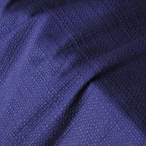 Pode incluir: Close-up de um tecido azul escuro texturizado. O material tem uma aparência tecida com um padrão sutil, criando uma aparência rica e dimensional. A cor do tecido é um azul escuro saturado, com sombras adicionando profundidade.