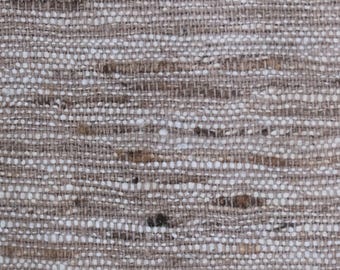 Può includere: Un tessuto intrecciato caratterizzato da una miscela di fili color beige chiaro, marrone chiaro e bianco. Il materiale presenta un motivo a tratteggio incrociato visibile e strutturato, con fibre orizzontali e verticali dal tono rustico.