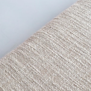 May include: Close-up of a beige fabric with a textured weave. The fabric has a subtle sheen and a slightly rough feel.