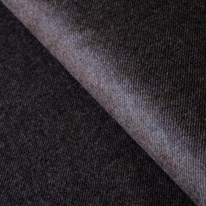 May include: A close-up shot of a dark grey fabric with a textured weave. The fabric has a slight sheen and a folded edge, revealing a hint of blue. The material appears to be heavy, suitable for upholstery or curtains.