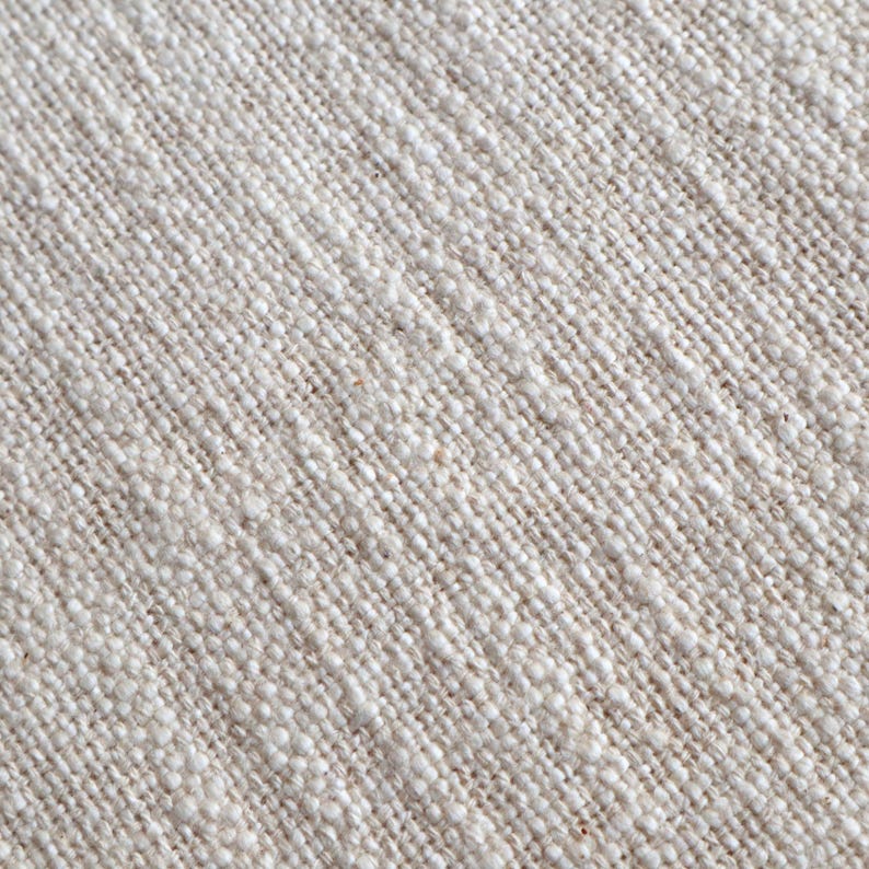 May include: Close-up of a natural linen fabric with a textured weave. The fabric is a light beige color.