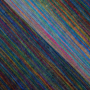 Op de afbeelding: Close-up van een kleurrijke stof met een diagonaal streepjespatroon. De stof heeft een mix van kleuren, waaronder blauw, groen, rood, geel en oranje. Het materiaal lijkt geweven te zijn, met zichtbare textuur en lichte vouwen.