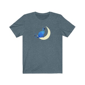 May include: A dark blue t-shirt with a blue cat sitting on a crescent moon. The cat and moon are both outlined in white.