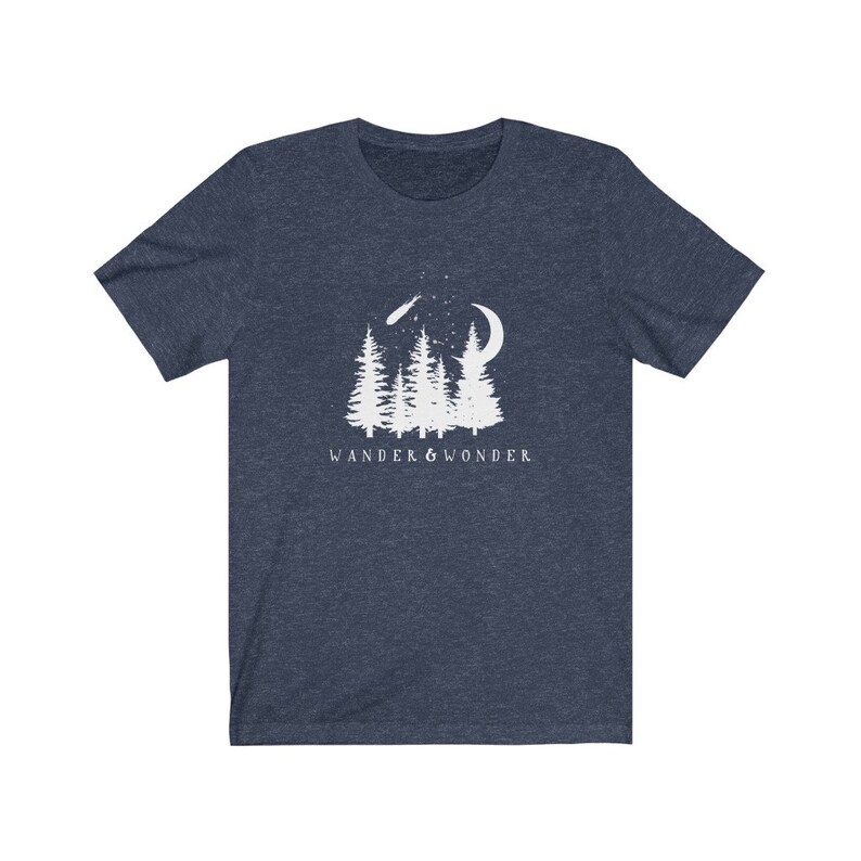 May include: A navy blue t-shirt with a white graphic of a crescent moon, shooting star, and pine trees. The text "WANDER & WONDER" is printed below the graphic.