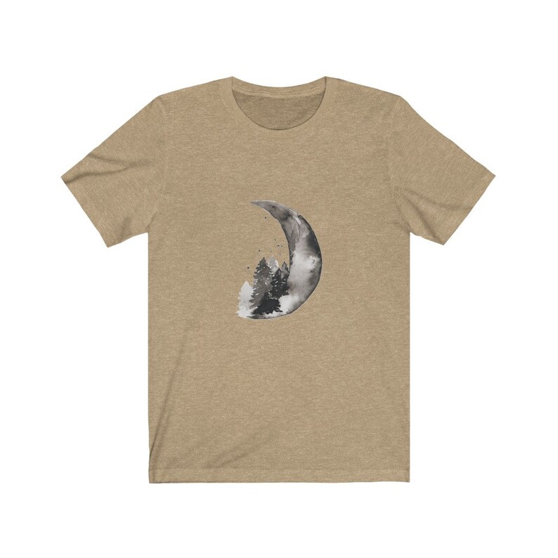 May include: A tan t-shirt with a black and white watercolor design of a crescent moon with a forest inside.